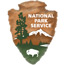 National Park Service Arrowhead, white capped mountian, tall green sequoia tree and white bison on a brown arrowhead.