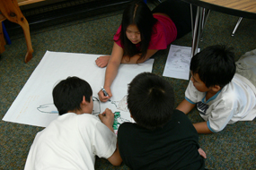 A group of students on the floor working on their animal with special adaptations for living in Alaska.