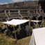 white tents with busy people to and fro lie at the edge of the fort walls