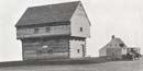 Grayscale picture of the Blockhouse.  The Neilson House is visible to the right and rear.
