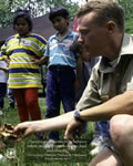 A small group of children gathered around a Forest Service employee who’s teaching them about nature.   The quote on the image says, there’s a great connectivity between nature and the power to inspire, heal, and educate.  – Audrey Peterman, President, Earthwise Productions, Inc.