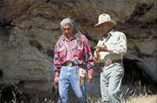 Native American and Forest Ranger walking in tall grass.