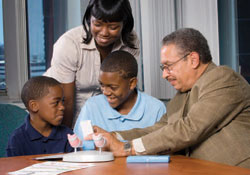 Dr. Floyd Malveaux teaches Rhonda, Jermid, and Jabeaux Brown of New Orleans to use a peak flow meter.