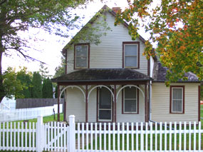 White house with brown trim and gingerbread decorations.