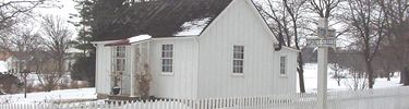 A small white cottage in the snow.