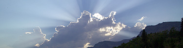 Sun rays behind clouds in Many Glacier