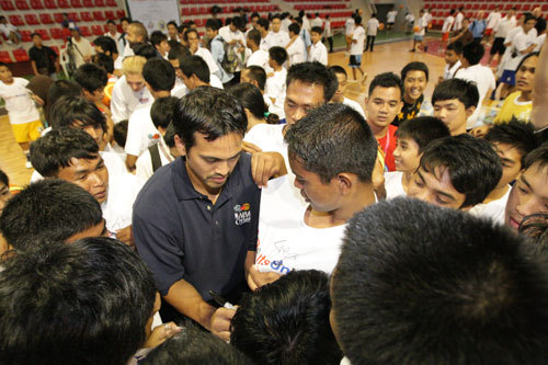 Photo of Coach ''Spoe'' signing the T-shirts of a group out of the 200 participants