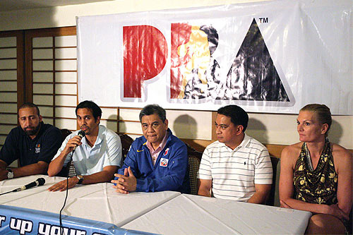 Photo of Erik answering questions at a press conference with Sue and Dave looking on