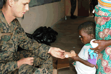 TALI, Ghana--Private First Class Zac J. Vaughn, U.S. Marine Corps, passes a wooden toy to a child who just received medical care in Tali, Ghana, in June, 2008. During an exercise called Shared Accord, U.S. service members partnered with Ghanaian medical professionals to administer medical and dental care to residents and treat livestock.(U.S. Marine Corps Photo by Master Sergeant Donald E. Preston)