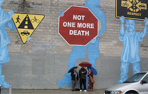 Photo of Mr. Alex Barboza, interpreter JR Dreyer and Ms. Amy Sananman, founder of the Groundswell Community Mural project, standing beside Not One More Death mural