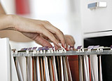 Womans hands going through files in cabinet.