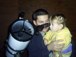 A child held up to look through a telescope
