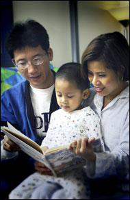 Photo: Parents reading a book with their child.