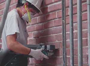 Worker using grinder to remove motar.