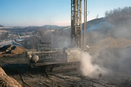 Large drilling machine in an area with low mountains.