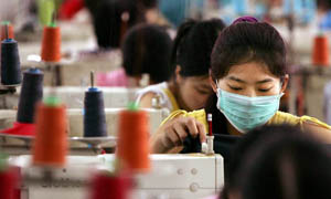 Chinese workers sew t-shirt in a textile factory in south China 