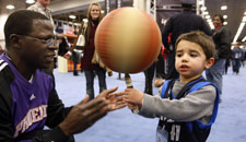 Phoenix Suns pregame team member Joseph Odhiambo helps Ryder Astorga, 3 of Dallas spin a basketball at the All Star Jam Session