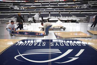 The floor is installed in Cowboys Stadium for Saturday's game between two top 10 teams in men's college basketball.