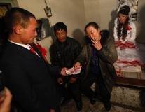 YUSHU, CHINA - DECEMBER 6:  Mother of the bride gives the groom Wang Yueming money after he called her mother during a wedding ceremony at the Wangjiacun Village on December 6, 2009 in Yushu of Jilin Province, China. The wedding of Nineteen-year-old Wang and eighteen-year-old Xiao Di, who...