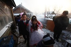 YUSHU, CHINA - DECEMBER 6:  Nineteen-year-old groom Wang Yueming and eighteen-year-old bride Xiao Di walk out of the bridal chamber at the Wangjiacun Village on December 6, 2009 in Yushu of Jilin Province, China. Wang and Xiao are farmers from the village. Usually in the wedding customs of...