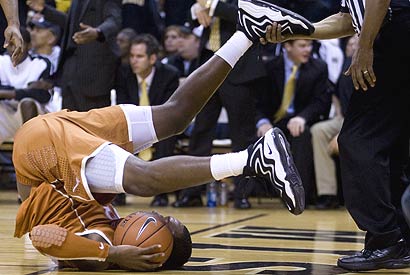 Referee Ed Hightower catches the foot of Texas' Jordan Hamilton after he was fouled and fell to the court during the first half.