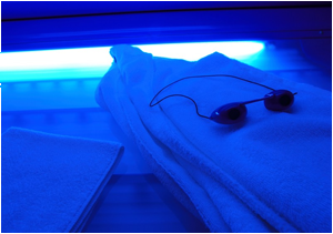 Photo of an open tanning bed, towel, and tanning goggles