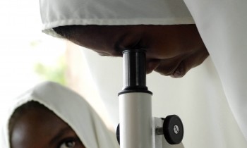 An African woman and child look through a microscope together