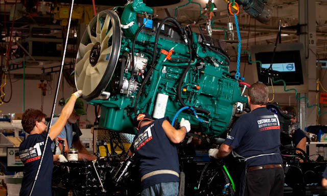 Workers at Volvo Trucks' New River Valley plant guide an engine into place.