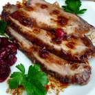 Slices of roasted leg of boar on a plate with cranberry sauce