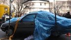 The car in which Iranian scientist Mostafa Ahmadi-Roshan was killed is removed from the street in Tehran