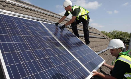 Workers install solar panels on a roof