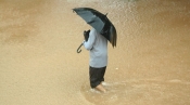 A man with an umbrella walks through floodwaters in Ambala, India, July 2010