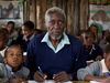 Photo: A grown man sits in a classroom with little children.