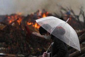 A man walks past burning debris in an area devastated by the March 11 earthquake and tsunami, in Minamisanriku town, Miyagi prefecture, April 23, 2011. REUTERS/Toru Hanai 