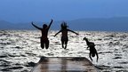 Three people jump in to a lake