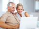 Couple sitting on a couch viewing a screen on a laptop