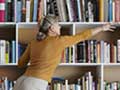 AARP Bookstore - woman reaches for book on bookshelf