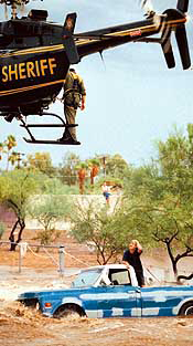 A helicopter attempts to rescue a man whose truck is in a flooded area.