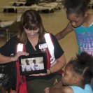 Photo: LaPlace, La., Sep. 7, 2012 -- Mar Tobiason, Red Cross shelter volunteer, shows a group of children a YouTube video featuring children living in a temporary shelter. The American Red Cross and FEMA are working with local, state and other federal agencies to assist residents affected by Hurricane Isaac.