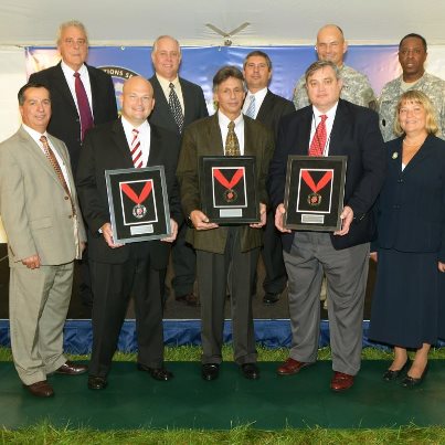 Photo: A Shingo Silver Medallion for operational excellence was presented to members of Tobyhanna Army Depot's Communications Systems Directorate's Communications Security Division at 10 a.m. Sept. 5 during an outside ceremony. It was the depot’s seventh Shingo Award but the first by an entire enterprise. Front row, from left, Ronald Cappellini, director of Communications Systems (CS) Directorate; Christopher Manning, project director communications security, Program Executive Office, Command, Control and Communications-Tactical (PEO C3T); Anthony Rubin, CS Directorate's Communications Security Division chief; A.D. Barksdale, director, Lean Six Sigma Deployment, CECOM; Lorraine Henry-Hunt, CS Directorate's deputy
director. Back Row, from left, Frank Zardecki, Tobyhanna Army Depot deputy commander; Shaun Barker, director of Operations and Assessment, Shingo Prize Office; William Sverapa, deputy program executive officer for (PEO C3T), Col. Gerhard P.R. Schröter, depot commander and Sgt. Maj. Kelvin Spencer,
depot sergeant major.