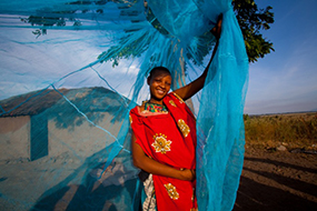 Young woman holding up mosquito net.