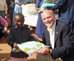 Photo of Rear Adm. Tim Ziemer handing packet to small child.