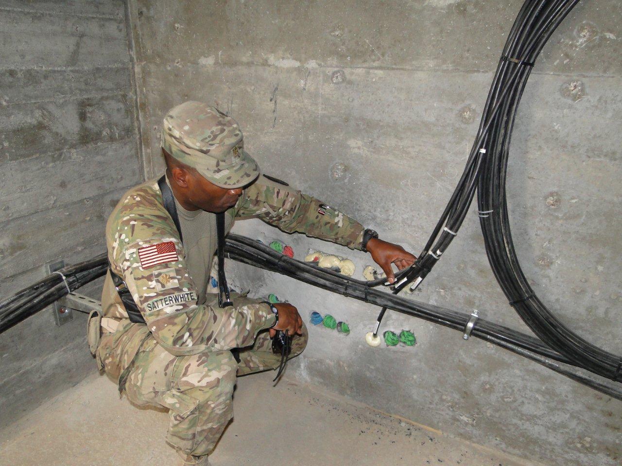 MAJ Reginald Satterwhite, an officer in charge of Afghan National Security Forces networks support operations under Deputy Command of Support Operations, NATO Training Mission-Afghanistan, inspects network cables at Forward Operating Base Delaram, Afghanistan, in Regional Support Command-Southwest May 15.