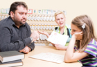 A girl talks with her father and teacher