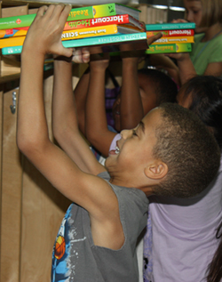 YWES putting books in cubby on first day of school.