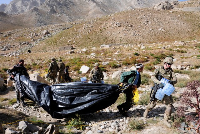 Spc. Luke Ledyard, a 10th Sustainment Brigade command group driver, carries water to a nearby truck while local Afghans help him with the parachute. Several Afghan civilians joined the Soldiers gathering supplies to lend their assistance.