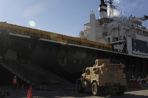 A mine-resistant, ambush-protected vehicle drives onto a commercial vessel at the Naval Weapons Stat...