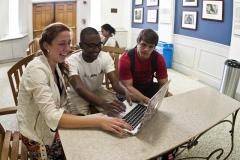 Group of three students looking at one laptop