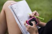 Picture of hands texting in front of notebook