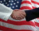 Two hands shake in front of american flag